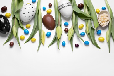 Photo of Flat lay composition with tulips, chocolate eggs and candies on white background, space for text. Easter celebration