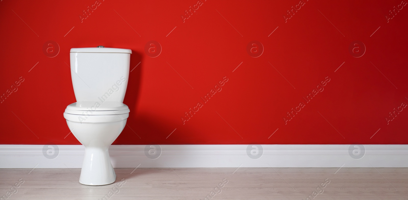 Image of Toilet bowl near red wall in restroom, space for text. Banner design