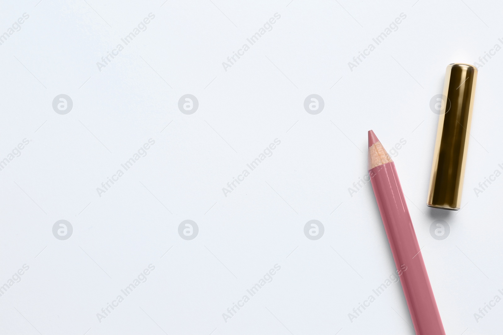 Photo of Lip pencil and cap on white background, top view. Cosmetic product