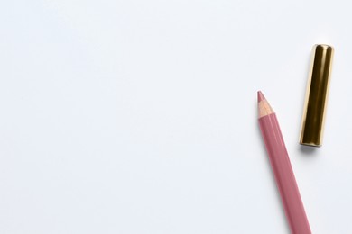 Photo of Lip pencil and cap on white background, top view. Cosmetic product