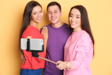 Young happy friends taking selfie against color background