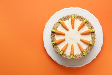 Dish with tasty carrot cake on orange background, top view. Space for text