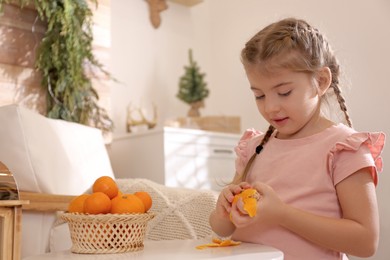 Cute little child peeling fresh tangerine at home