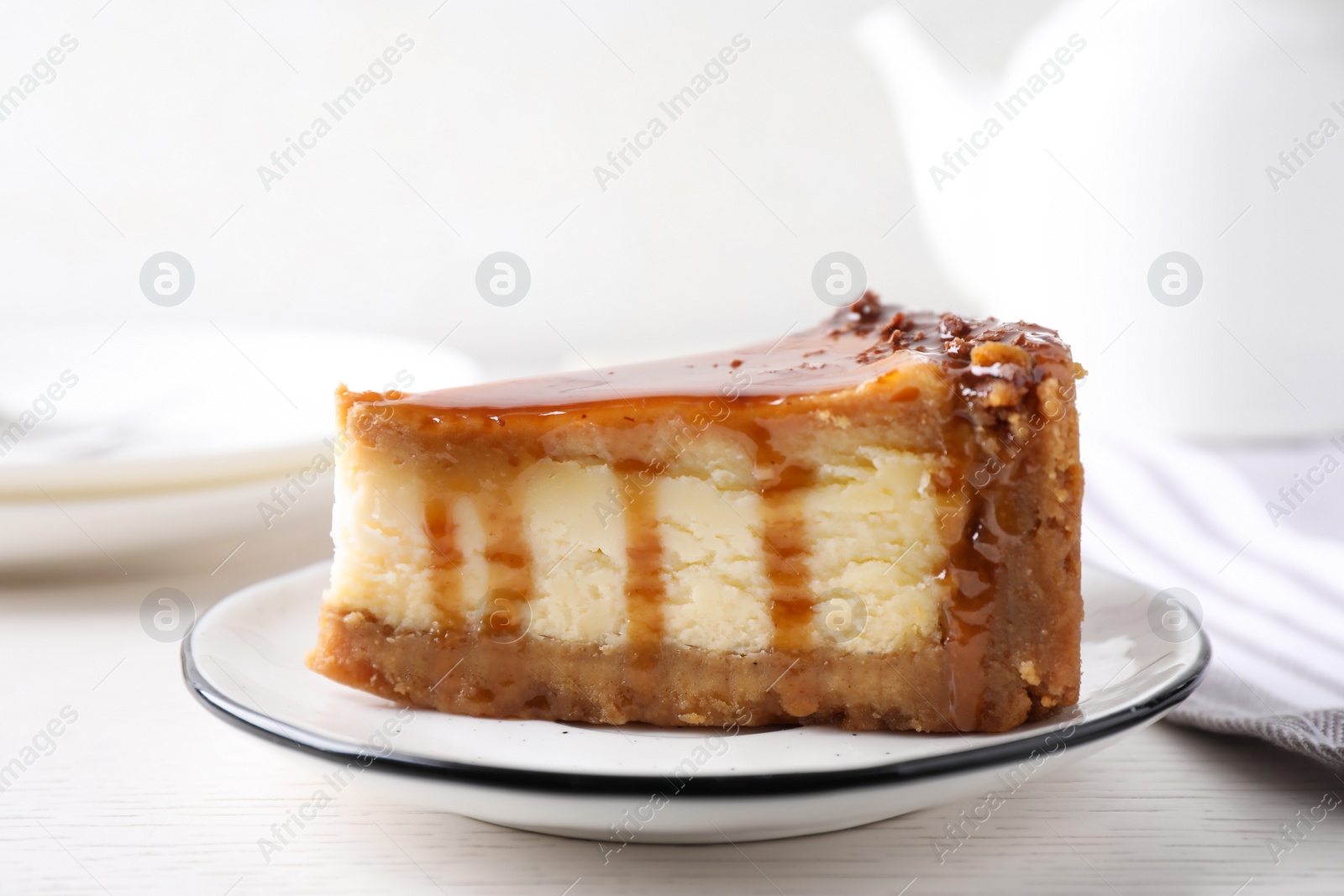 Photo of Piece of delicious cake with caramel served on white wooden table