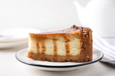 Photo of Piece of delicious cake with caramel served on white wooden table