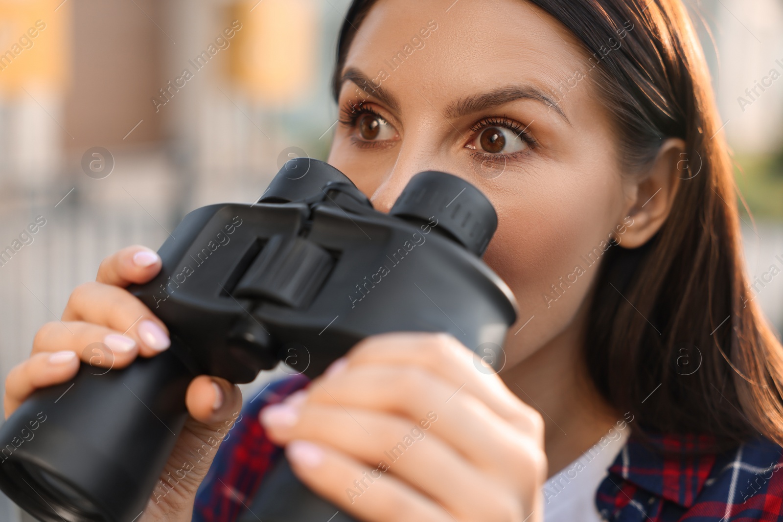 Photo of Concept of private life. Curious young woman with binoculars spying on neighbours outdoors, closeup