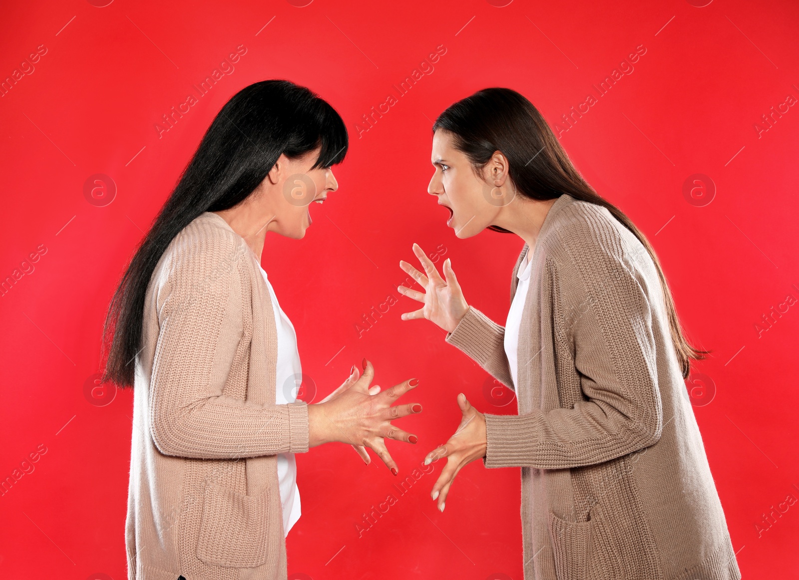 Photo of Young daughter and her mature mother arguing on color background