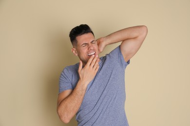 Handsome tired man yawning on beige background