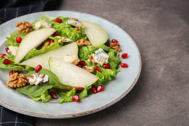 Photo of Delicious pear salad on dark textured table, closeup