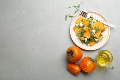 Photo of Delicious persimmon salad with blue cheese and orange served on light grey table, flat lay. Space for text