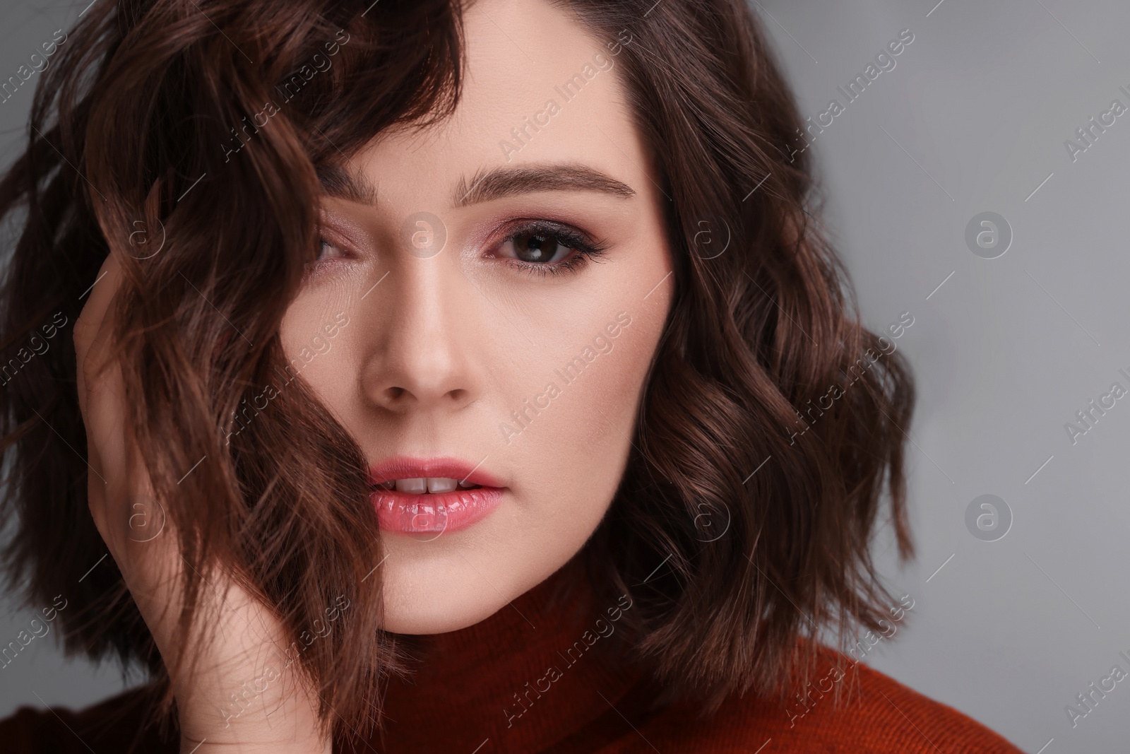 Photo of Beautiful young woman with wavy hairstyle on grey background