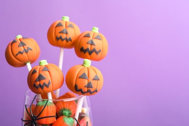 Delicious Halloween themed cake pops on violet background, closeup. Space for text