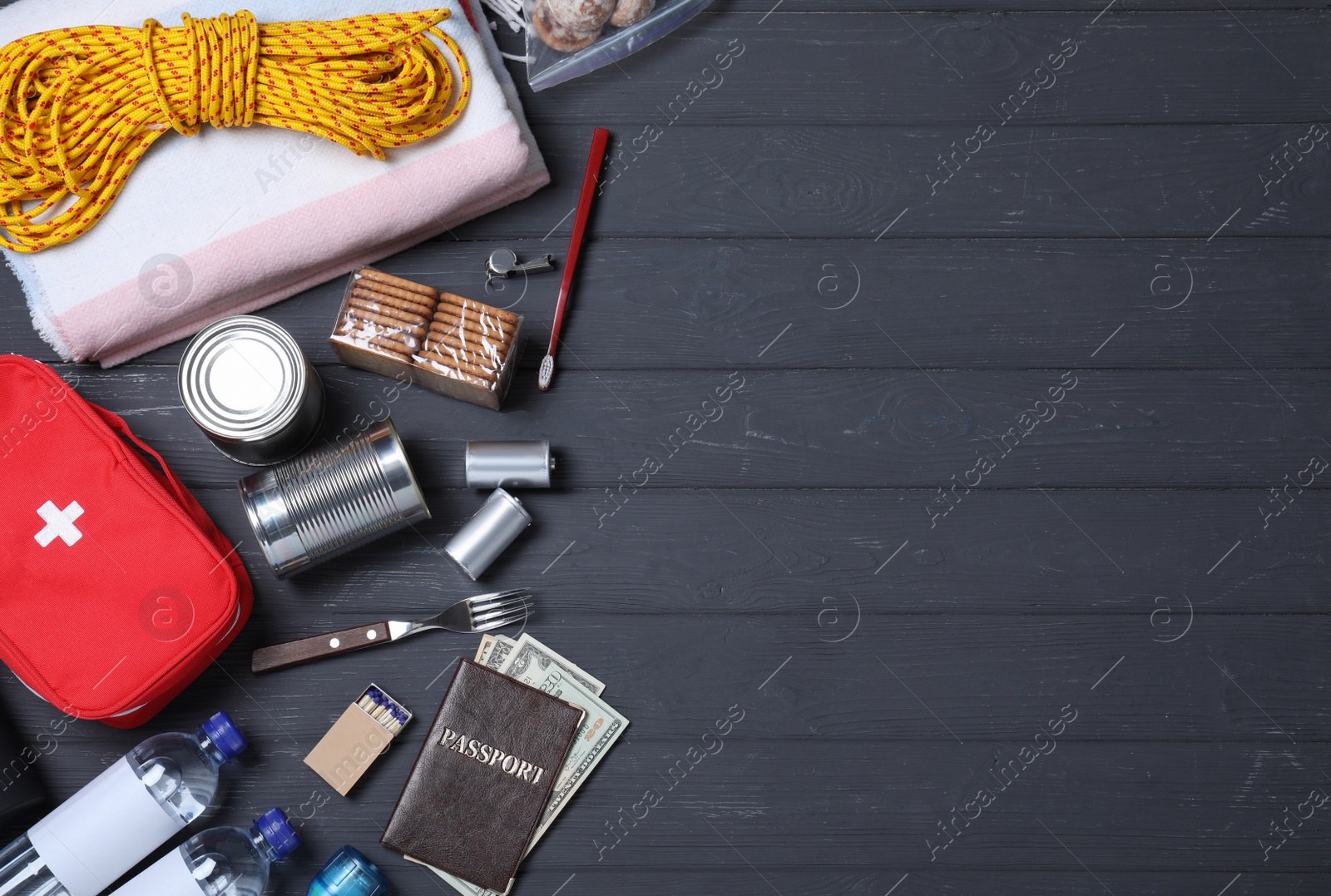 Photo of Earthquake supply kit on black wooden table, flat lay. Space for text