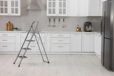 Photo of New metal stepladder on floor in kitchen, space for text