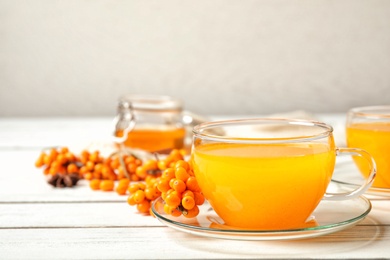 Delicious sea buckthorn tea and fresh berries on white wooden table