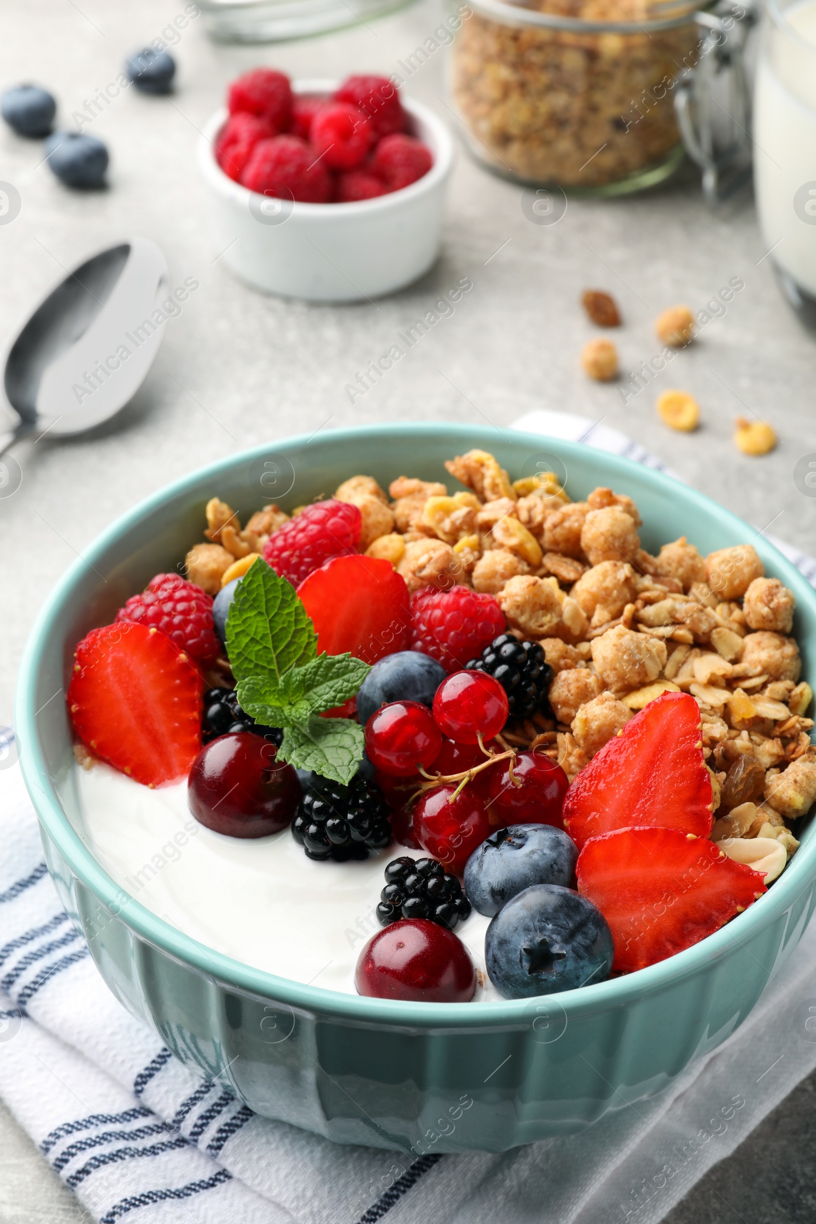 Photo of Bowl with tasty granola and berries on light grey table. Healthy meal
