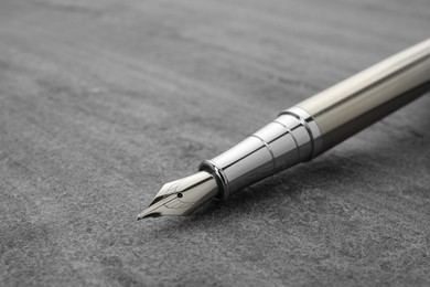 Stylish silver fountain pen on grey textured table, closeup. Space for text