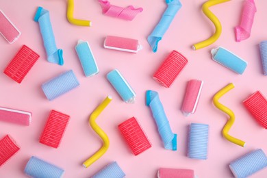 Photo of Different hair curlers on pink background, flat lay. Styling tool