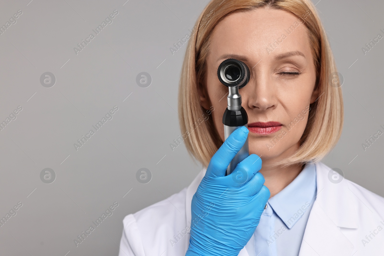 Photo of Dermatologist using dermatoscope on grey background. Space for text