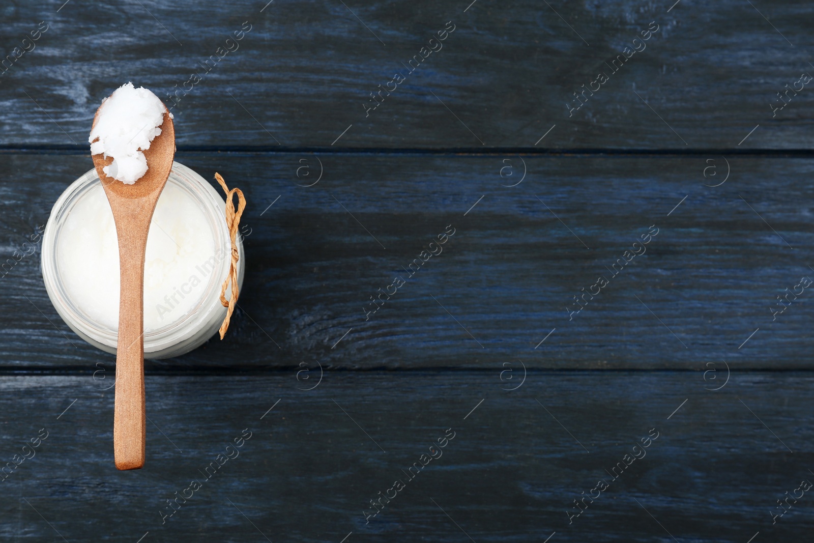 Photo of Coconut oil on dark wooden table, top view with space for text. Cooking ingredient