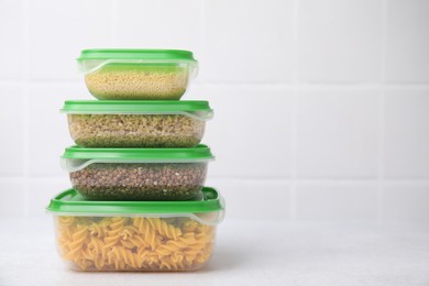 Plastic containers filled with food products on white table near tiled wall. Space for text