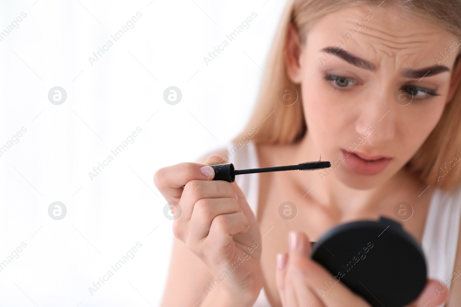 Photo of Emotional woman holding mascara brush with fallen eyelashes indoors