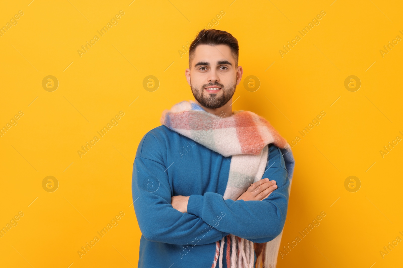 Photo of Smiling man in warm scarf on yellow background