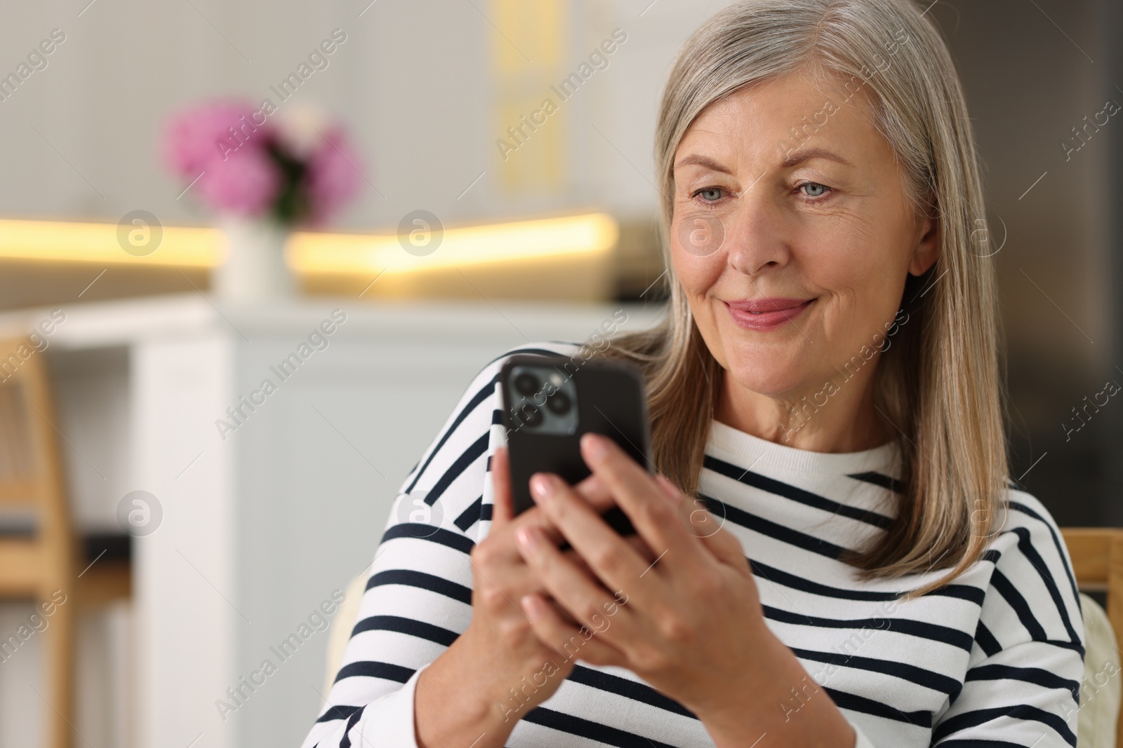 Photo of Senior woman using mobile phone at home, space for text