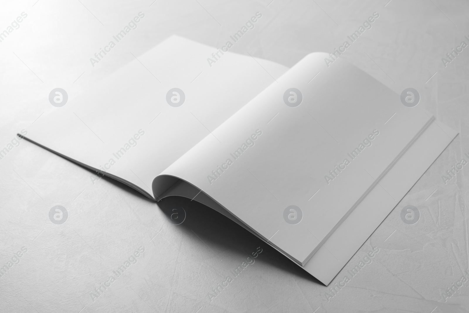 Photo of Open notebook with blank paper sheets on grey textured table. Mockup for design