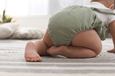 Photo of Cute baby crawling on floor at home, closeup