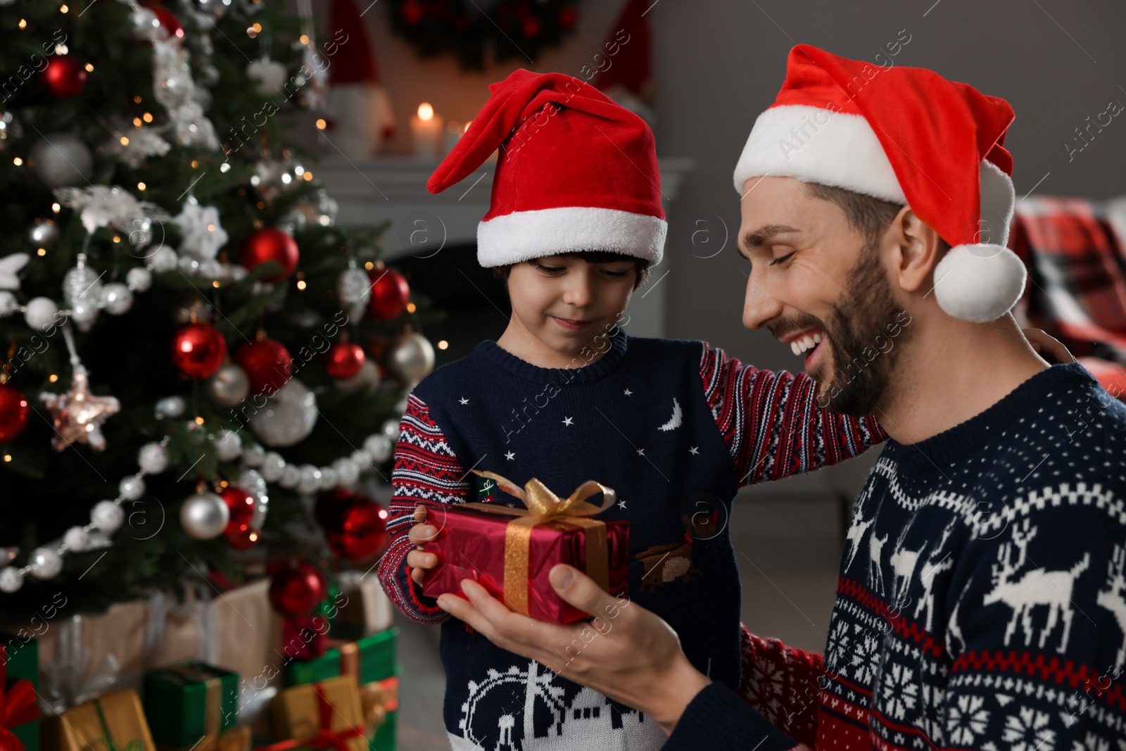 Photo of Cute son giving present to his father at home. Christmas celebration