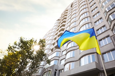 National flag of Ukraine fluttering near building on sunny day