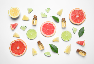 Flat lay composition with bottles of citrus essential oil on white background