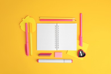 Flat lay composition with open notebook and different school stationery on yellow background, space for text. Back to school