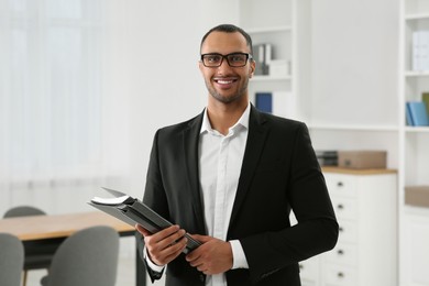 Smiling young businessman with folders in office