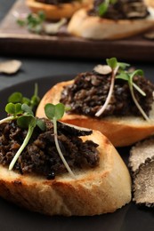 Delicious bruschettas with truffle sauce and microgreens on table, closeup