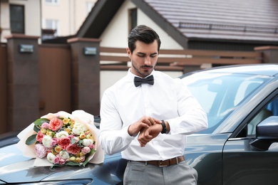 Photo of Young handsome man with beautiful flower bouquet near car outdoors