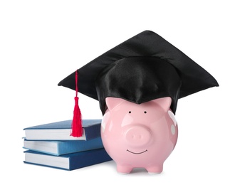 Photo of Piggy bank with graduation hat and books isolated on white