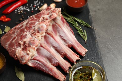 Photo of Raw ribs with spices on slate board, closeup