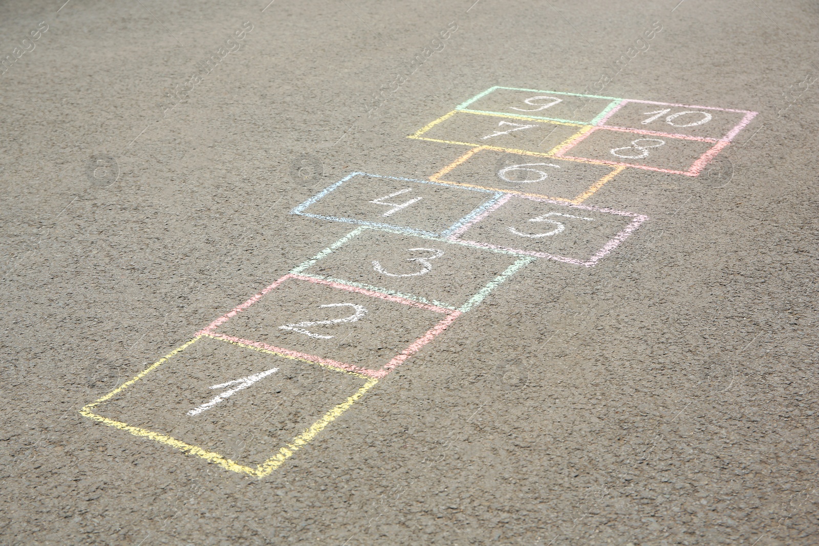 Photo of Hopscotch drawn with colorful chalk on asphalt outdoors