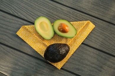 Halves and whole fresh avocados on wooden table, top view