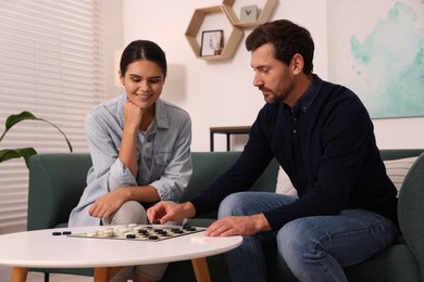 Couple playing checkers at coffee table at home