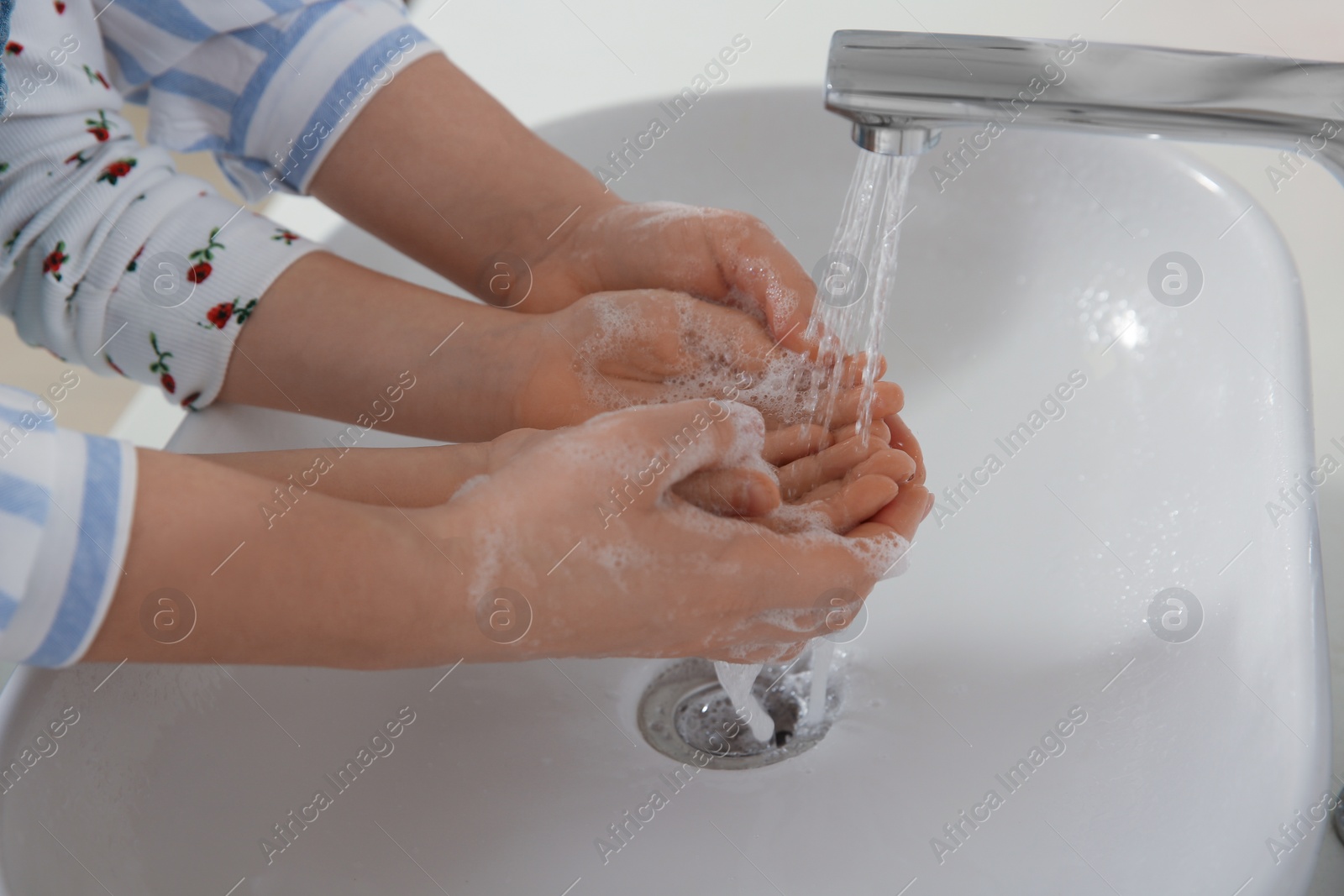 Photo of Mother and daughter washing hands with liquid soap together, closeup