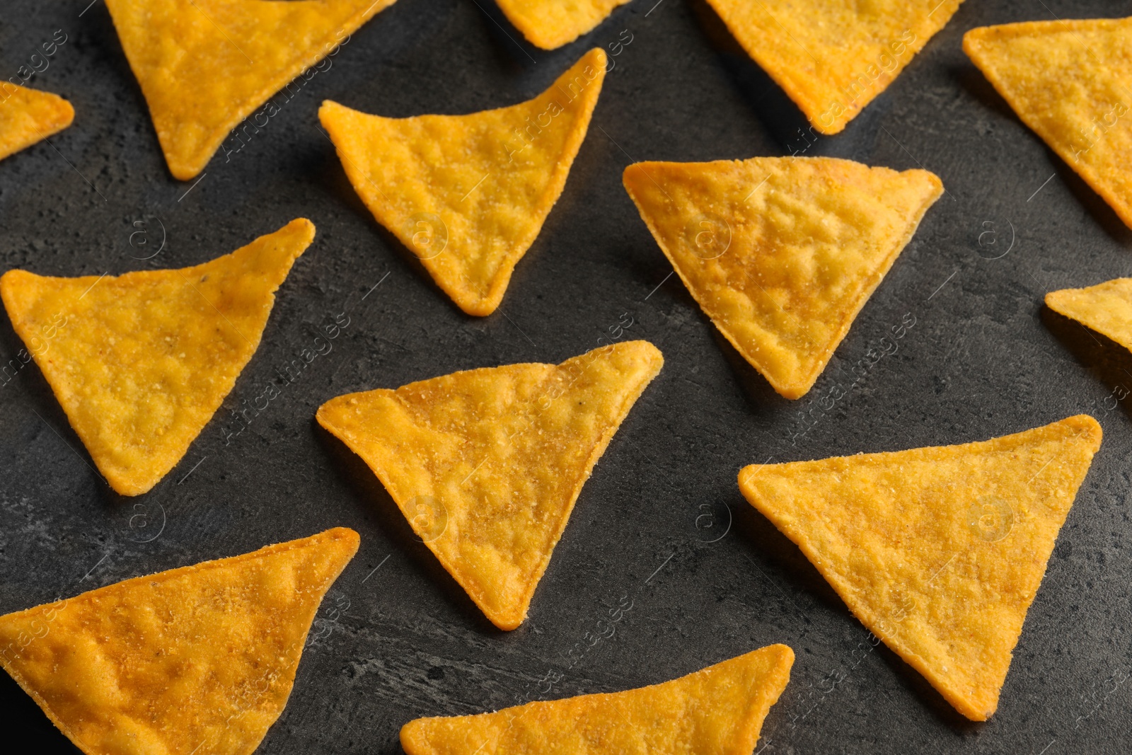 Photo of Composition of tasty tortilla chips (nachos) on grey table