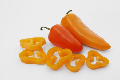 Photo of Cut and whole orange hot chili peppers on white background