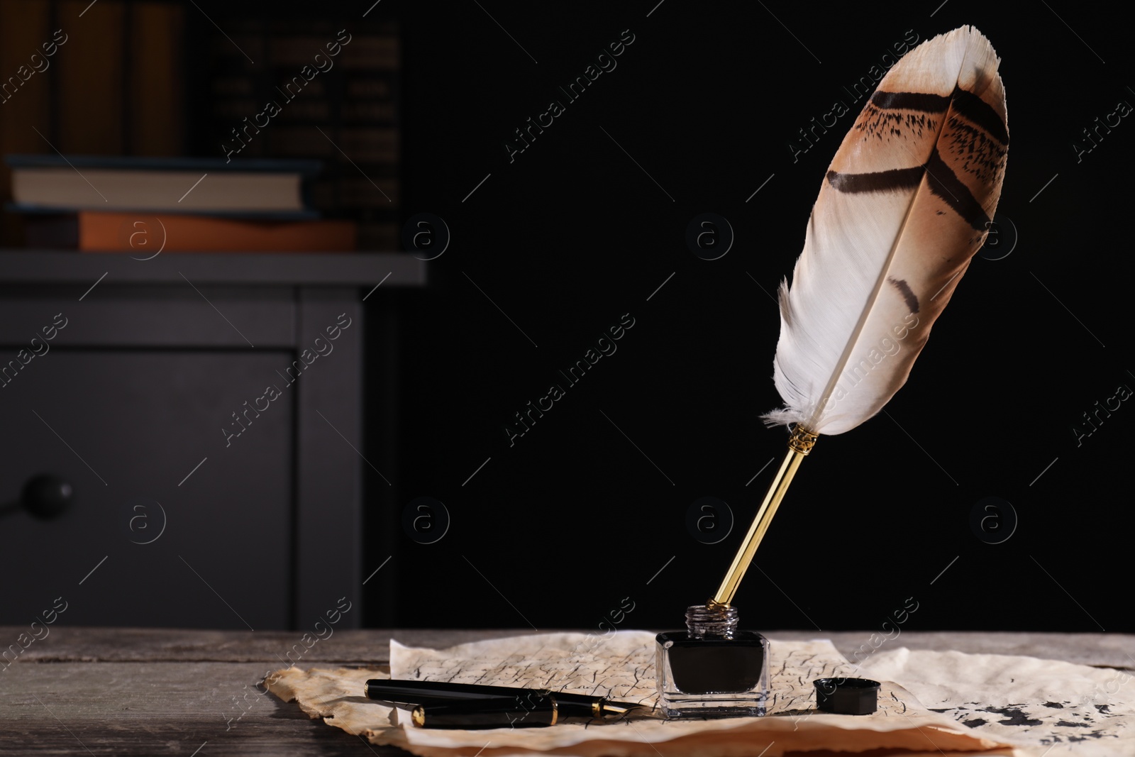 Photo of Inkwell with feather pen and vintage parchment on wooden table indoors. Space for text