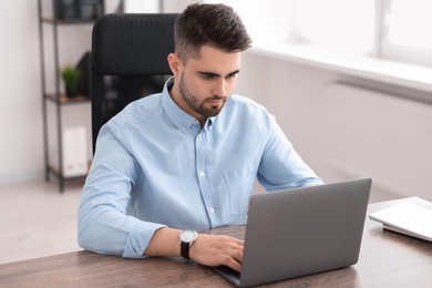 Photo of Young programmer working with laptop in office