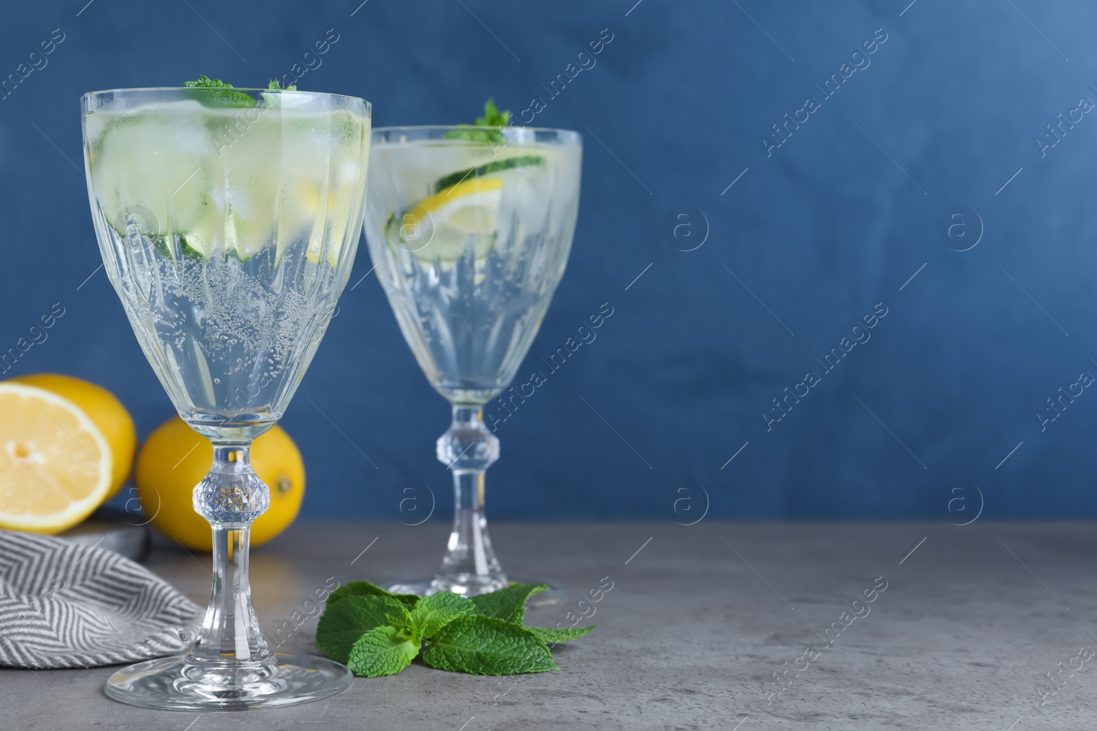 Photo of Refreshing water with cucumber, lemon and mint on grey table. Space for text