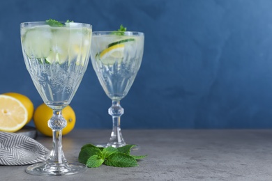 Refreshing water with cucumber, lemon and mint on grey table. Space for text