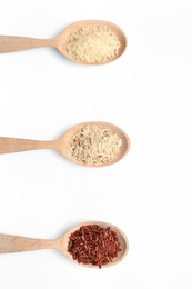 Photo of Spoons with different types of uncooked rice on white background, top view